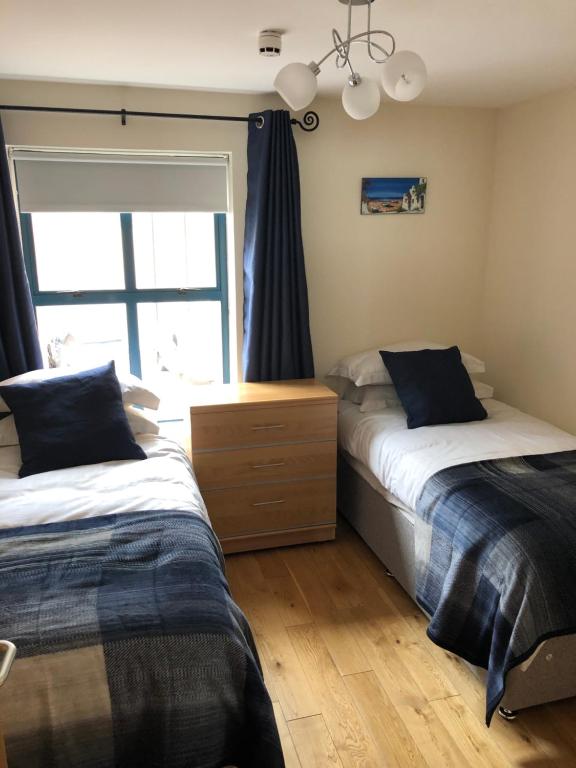 1 dormitorio con 2 camas y ventana en Newcastle Seafront Apartment with Wifi and Parking en Newcastle