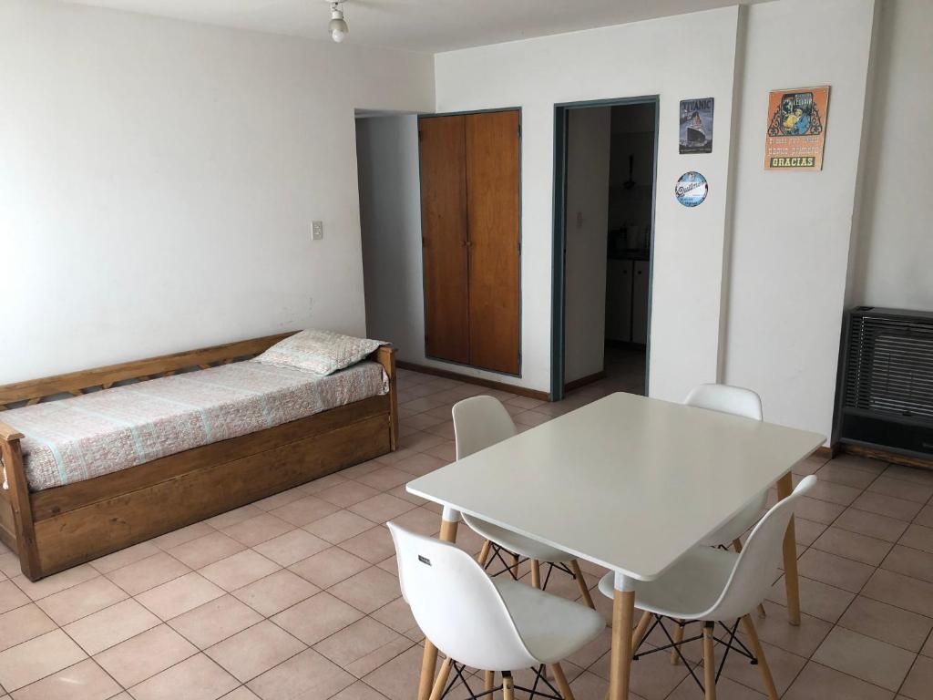 a room with a bed and a table and chairs at Apartamento Pacifico Suites Centro in Bahía Blanca