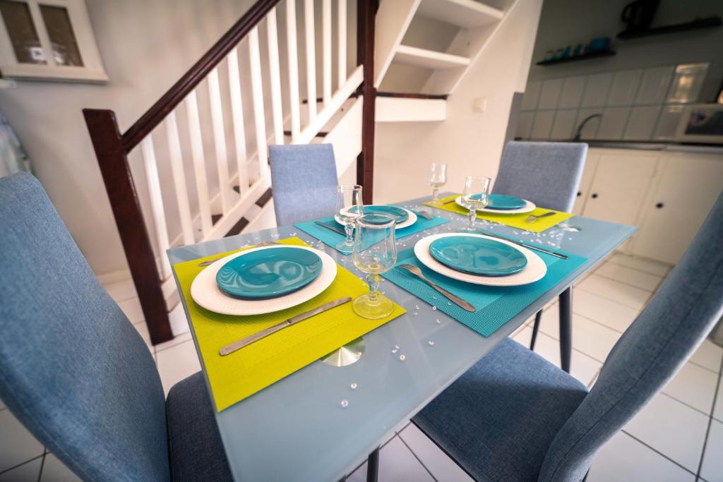 una mesa azul con sillas azules, platos y vasos en Domaine De Marly, 3 étoiles, en Sainte-Anne