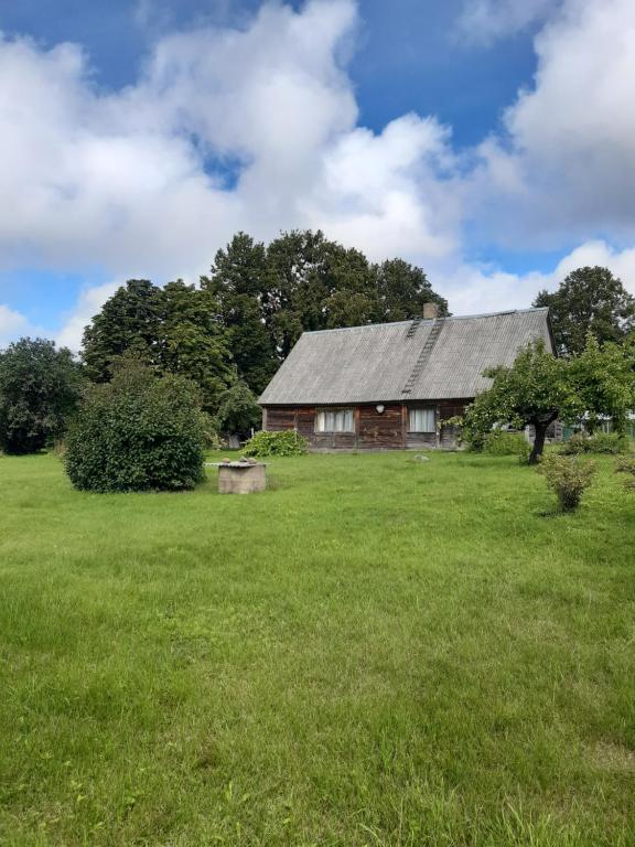 an old barn in a field with a green field at Brīvdienu lauku māja Budnieki in Akmeņdziras