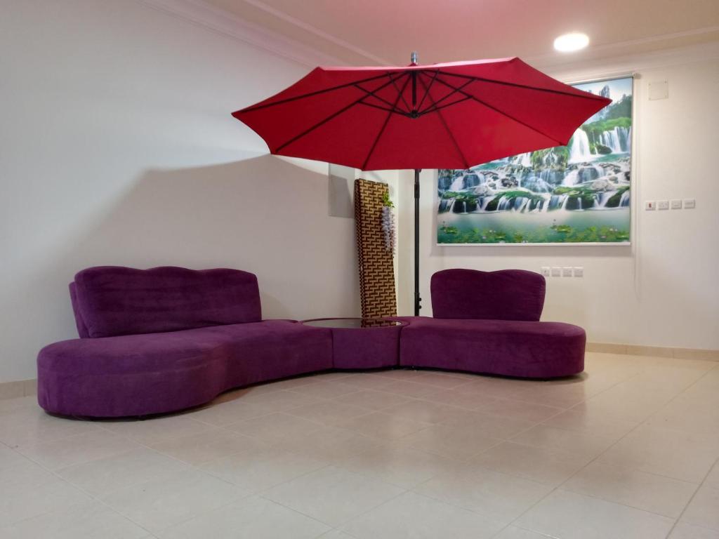 a living room with two purple chairs and a red umbrella at شقة دورين 4 غرف نوم في منطقة هادئه - لغير المدخنين - تقع في الدور الأول - لايوجد مصعد - تبعد عن وسط بريده 8 دقائق in Buraydah