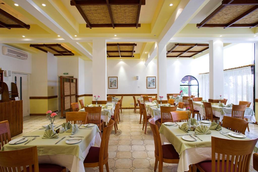 a dining room with tables and chairs with white tablecloths at Club Aphrodite in Erimi