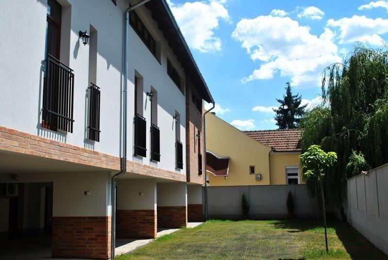 un edificio blanco con ventanas y un patio de césped en Maja Apartman, en Gyula