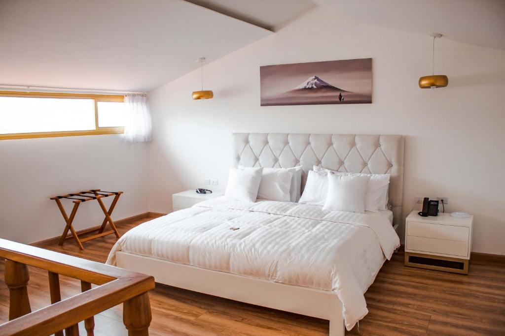 Adamas House Hotel Boutique في كيتو: غرفة نوم بيضاء مع سرير أبيض كبير مع وسائد بيضاء