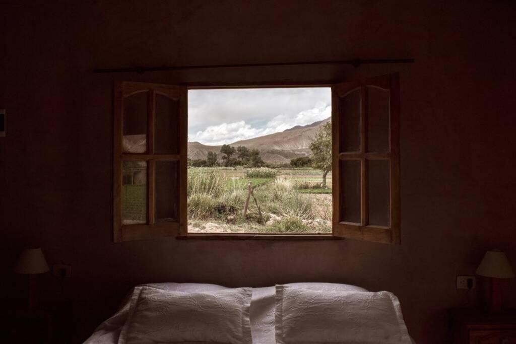 ventana en un dormitorio con vistas al campo en Ruphay: Cabaña equipada con vista a los cerros en el campo en Maimará