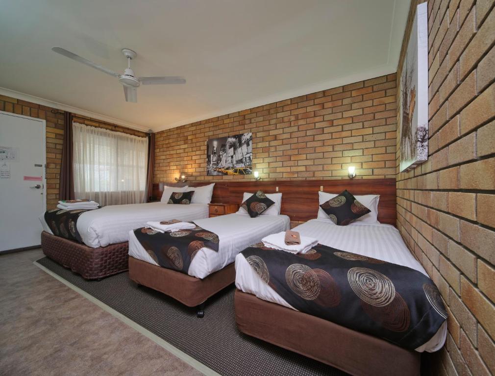 een slaapkamer met 2 bedden en een bakstenen muur bij City View Motel in Warwick