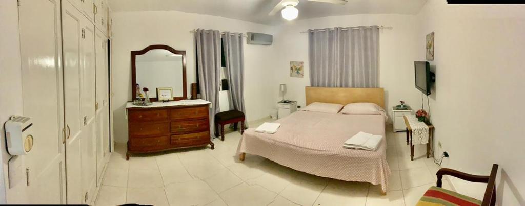 a bedroom with a bed and a dresser and a mirror at Posada Dilia del Alba in Santo Domingo