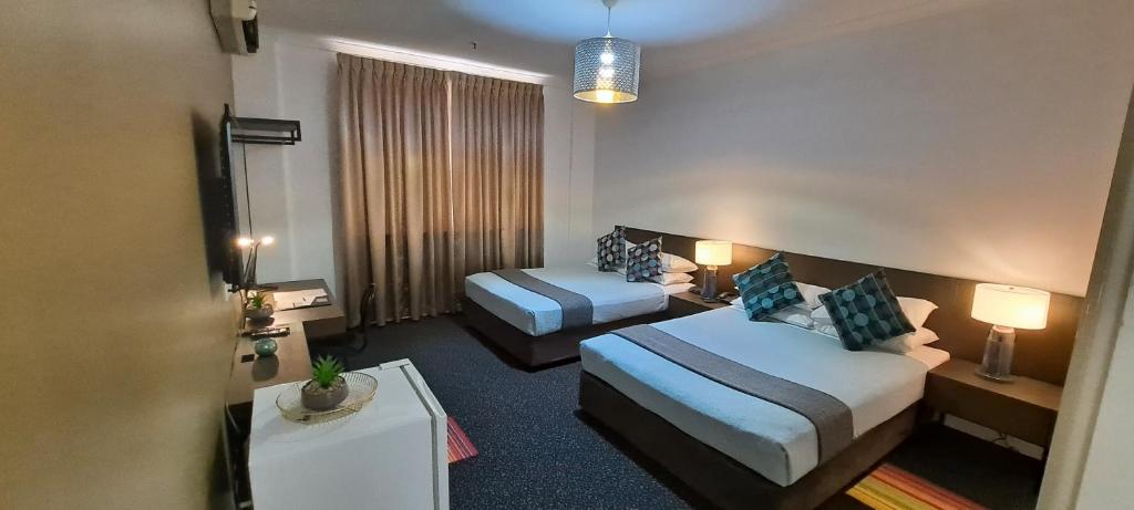 a hotel room with two beds and a table at Criterion Hotel Perth in Perth