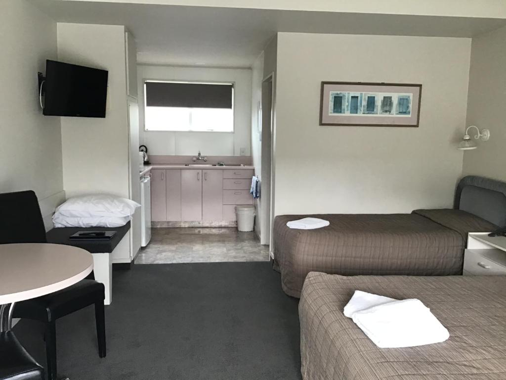 Habitación pequeña con 2 camas y lavamanos en Helensborough Motor Inn, en Balclutha