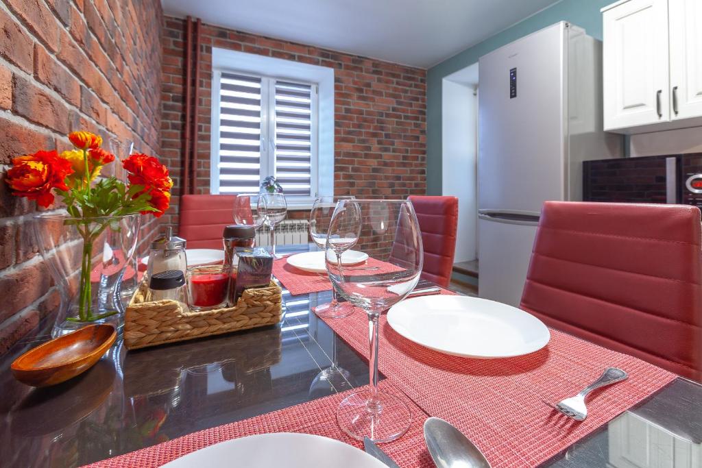 una mesa de comedor con sillas rojas y copas de vino en Уютные Апартаменты RentPlaza в центре города 24x7 дистанционно en Samara