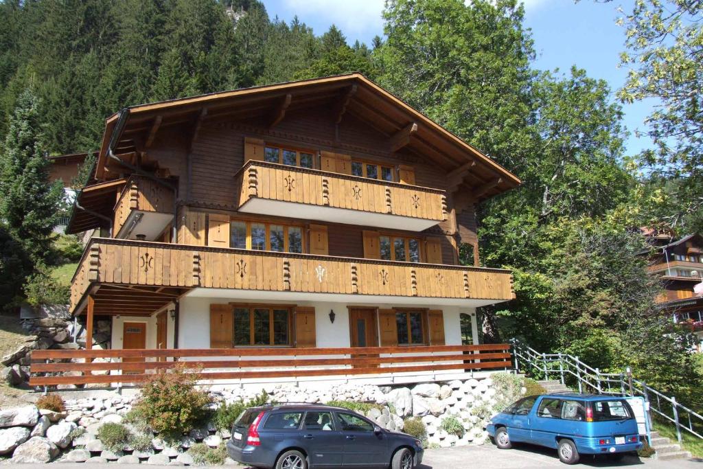 ein Haus mit zwei Autos, die davor geparkt sind in der Unterkunft Ferienwohnung Senggi in Adelboden