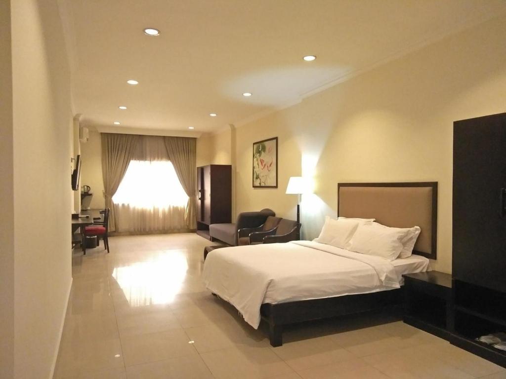 a large hotel room with a bed and a desk at Almond Hotel Sothearos in Phnom Penh