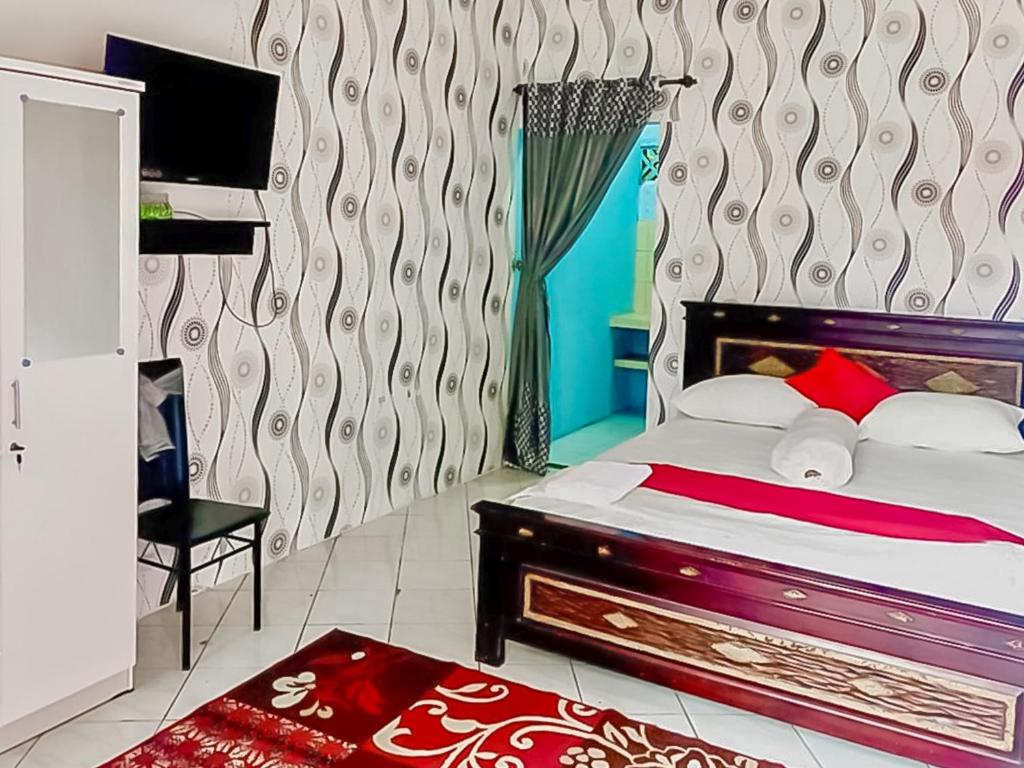 a bedroom with a bed and a chair and a window at Homestay Levida Mitra RedDoorz in Samarinda