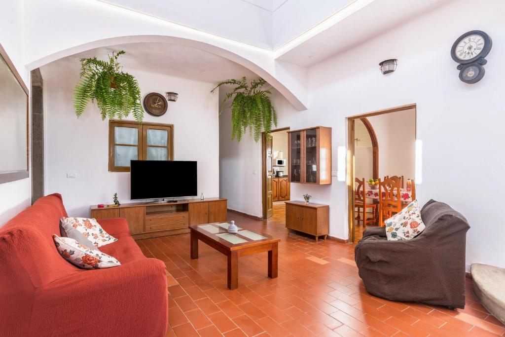 a living room with red furniture and a flat screen tv at El Huerto in Firgas