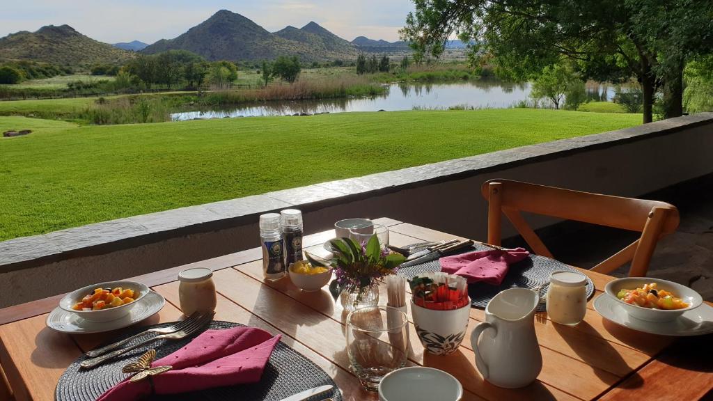 a wooden table with food and a view of a lake at Big Sky Ranch in Colesberg