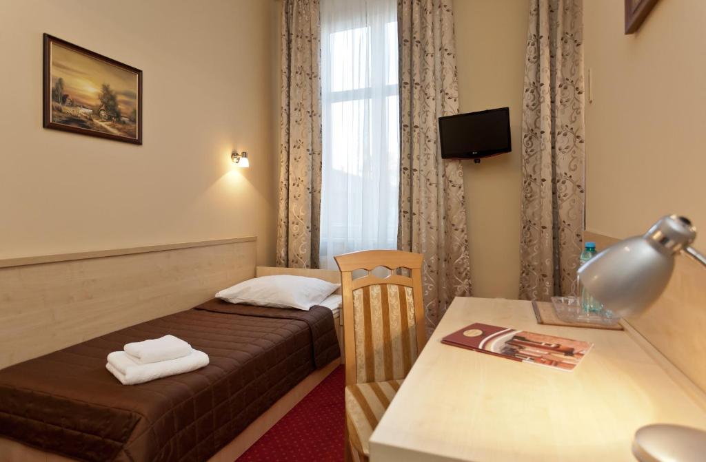 a hotel room with a bed and a desk with a table at Hotel Maksymilian in Krakow