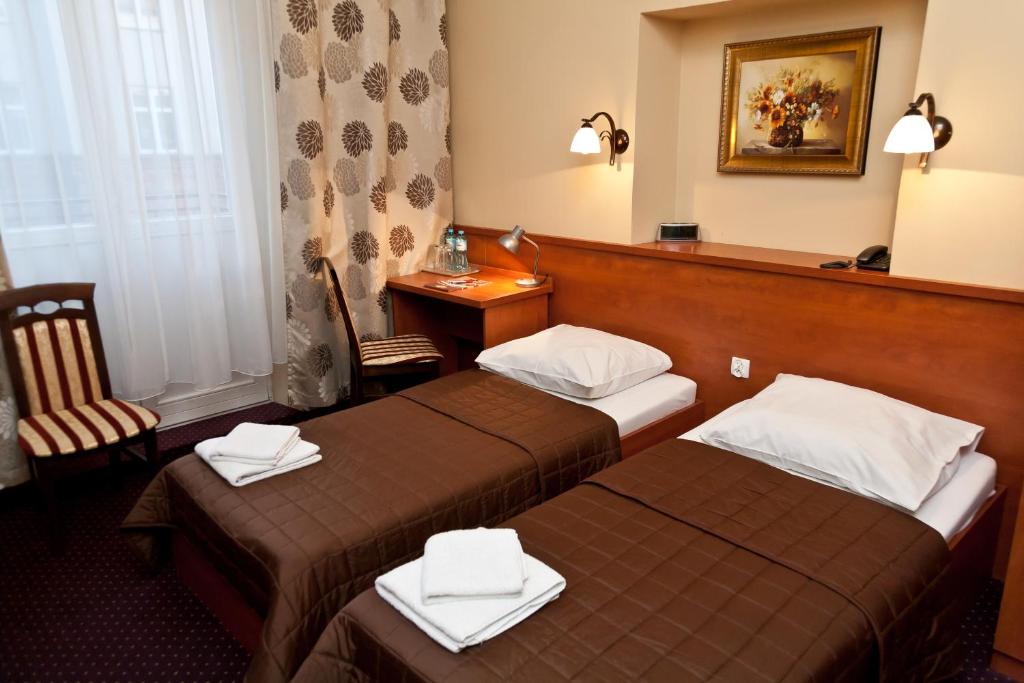 a hotel room with two beds and a desk at Hotel Maksymilian in Krakow