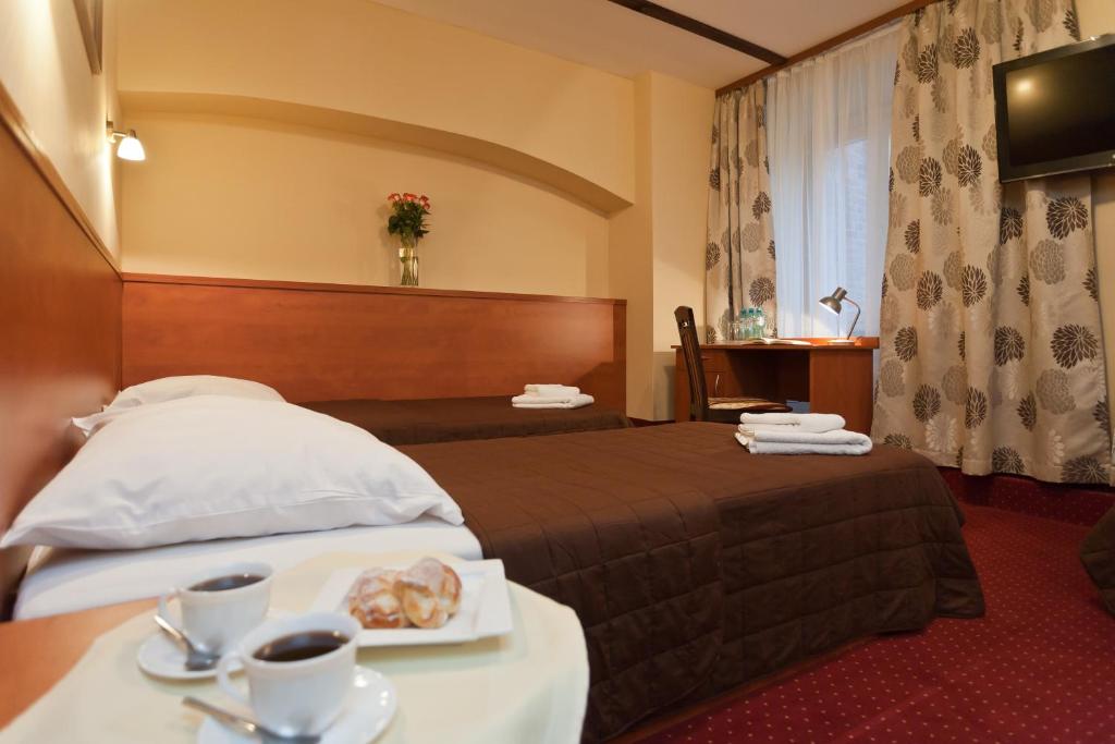 a hotel room with a bed with a tray of food on a table at Hotel Maksymilian in Krakow