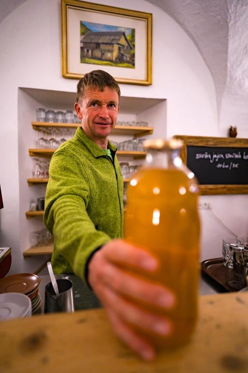 a man sitting at a table holding a bottle at Tourist Farm Šenkova Domačija in Zgornje Jezersko