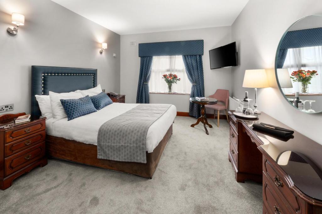 a bedroom with a bed and a sink and a mirror at Rathkeale House Hotel in Limerick