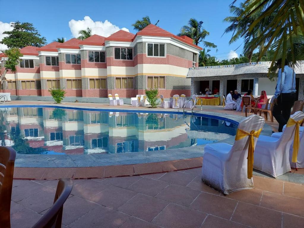 a hotel with a swimming pool in front of a building at coral beach resort in Mahabalipuram