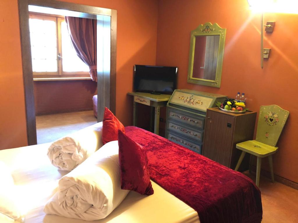 a bedroom with a bed with red pillows and a mirror at Hotel Punta Maquignaz in Breuil-Cervinia