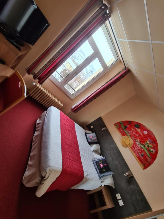 a bedroom with a bed with a red and white blanket at HOSTELLERIE du CANTAL in Murat
