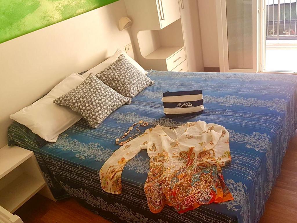 a bed with a blue comforter and pillows on it at Hotel Arena in Rimini