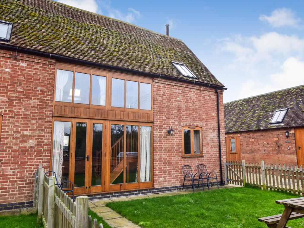 an extension to a brick house with sliding glass doors at Granary, Oosland Farm in Bidford