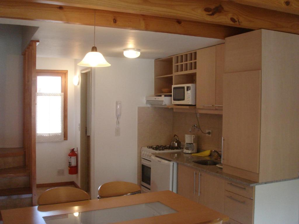 cocina con mesa, sillas y microondas en Departamento San Martin III en San Martín de los Andes