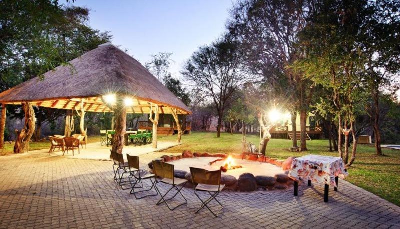 a tent with a table and chairs and a fire at Mulati Luxury Safari Camp in Gravelotte