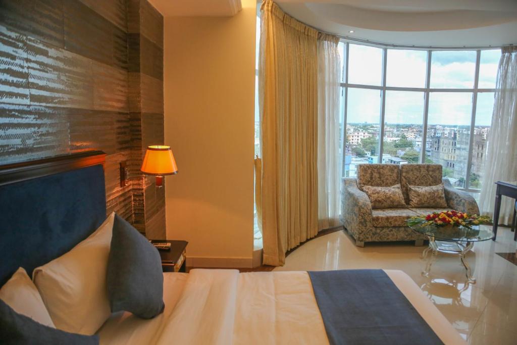 sypialnia z łóżkiem i krzesłem oraz dużym oknem w obiekcie Hotel Valley Garden w mieście Srihotto