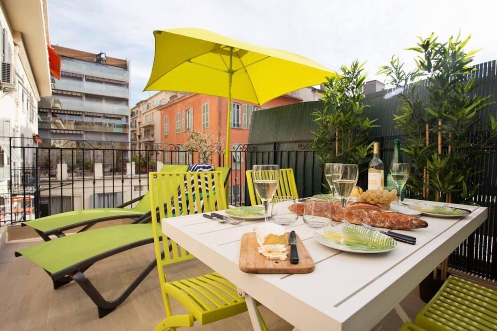 - une table avec de la nourriture sur un balcon avec un parasol jaune dans l'établissement F2 TERRASSE, MODERNE, HYPER CENTRE, CLIM, ASCENSEUR- dubouchage, à Nice