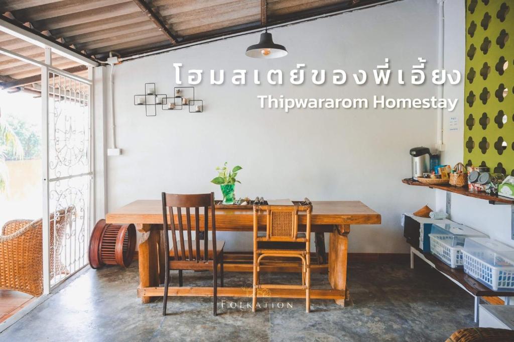 uma sala de jantar com uma mesa de madeira e cadeiras em Thipwararom homestay em Takua Pa
