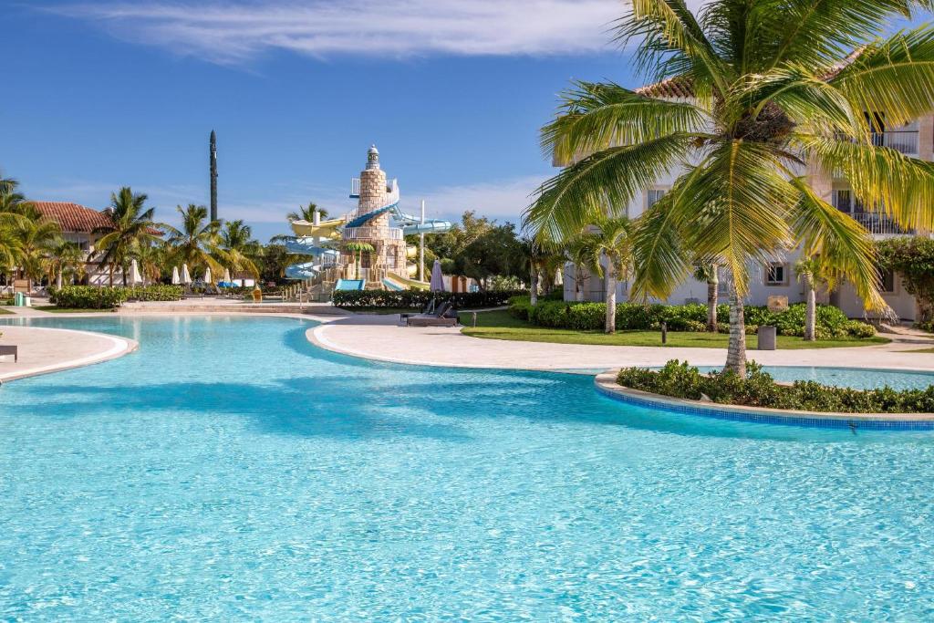 einen Pool in einem Resort mit Palmen und einem Gebäude in der Unterkunft Beachfront Cadaques Smart Tv Fullkitchenrest in Bayahibe