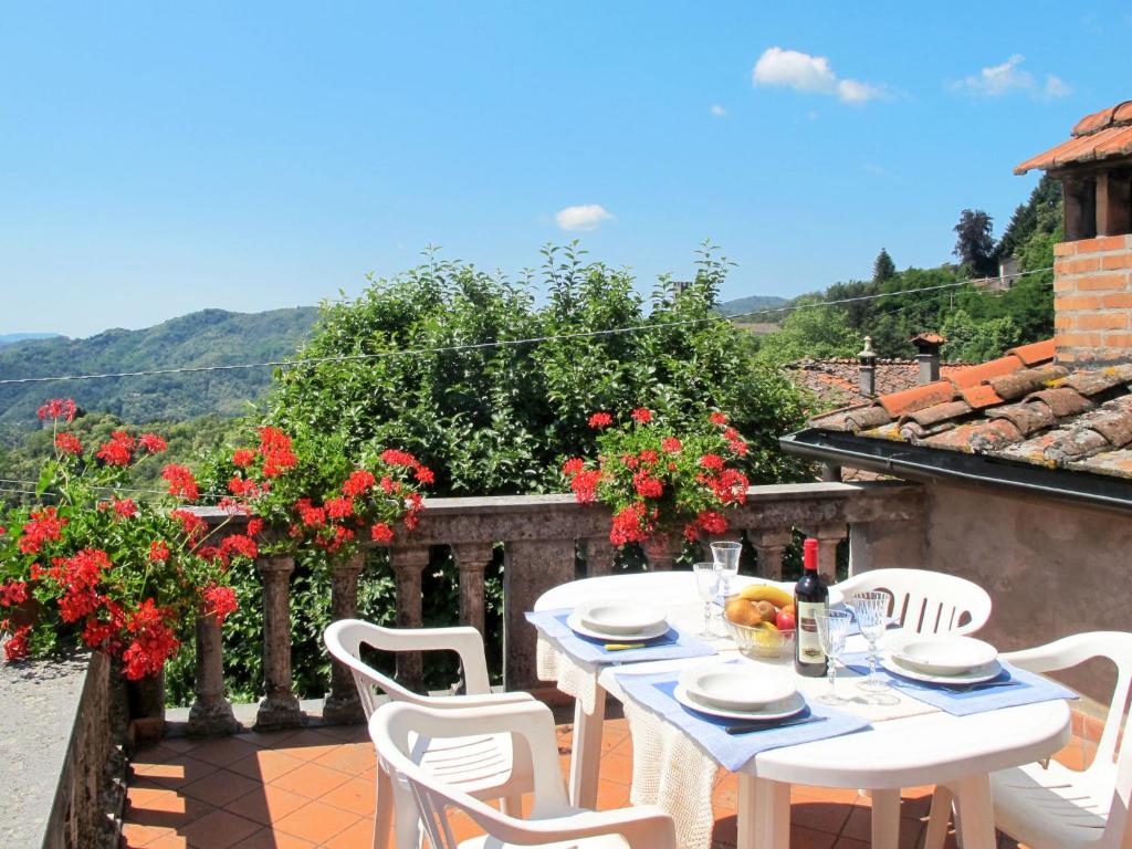 einen weißen Tisch und Stühle auf einem Balkon mit Blumen in der Unterkunft Apartment Pervinca by Interhome in Gello