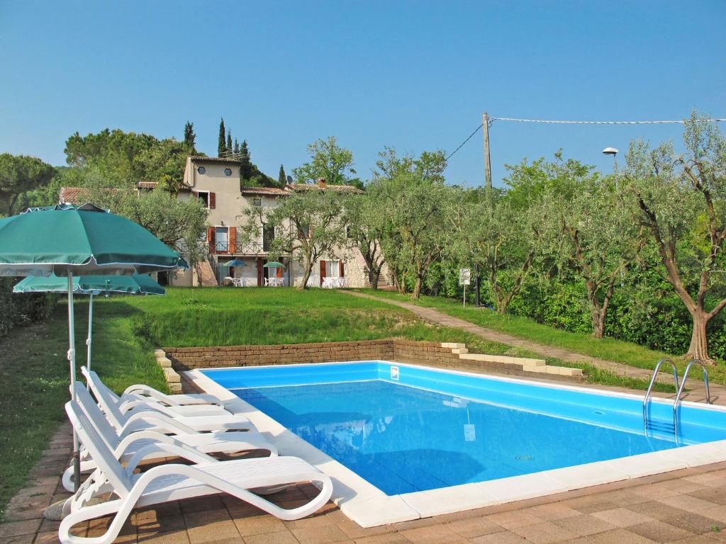 a swimming pool with lounge chairs and an umbrella at Apartment Ca' Pignoi-5 by Interhome in Garda