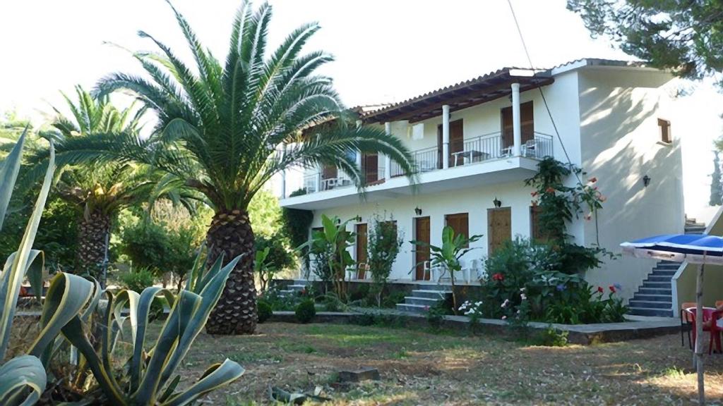 a white house with palm trees in front of it at Villa Alexandra in Roda