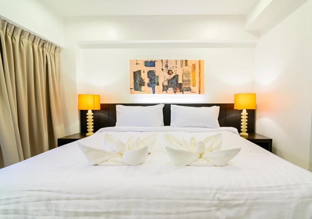um quarto com uma cama branca com duas flores brancas em UMA Residence em Bangkok