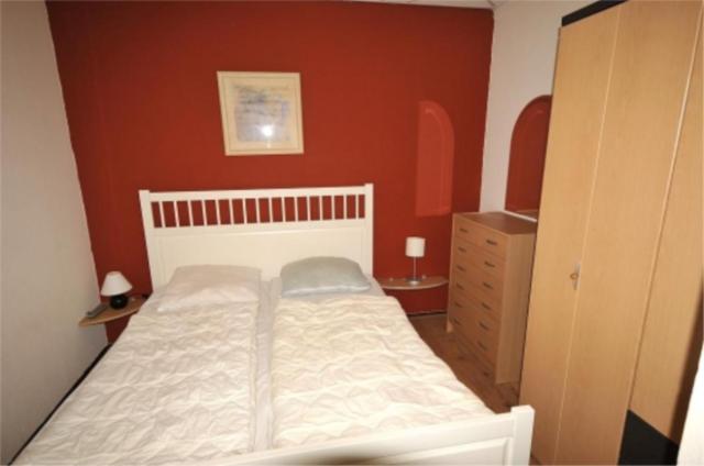 ユリアーナドルプにあるApartment 105の白いベッドと赤い壁が備わるベッドルーム1室が備わります。