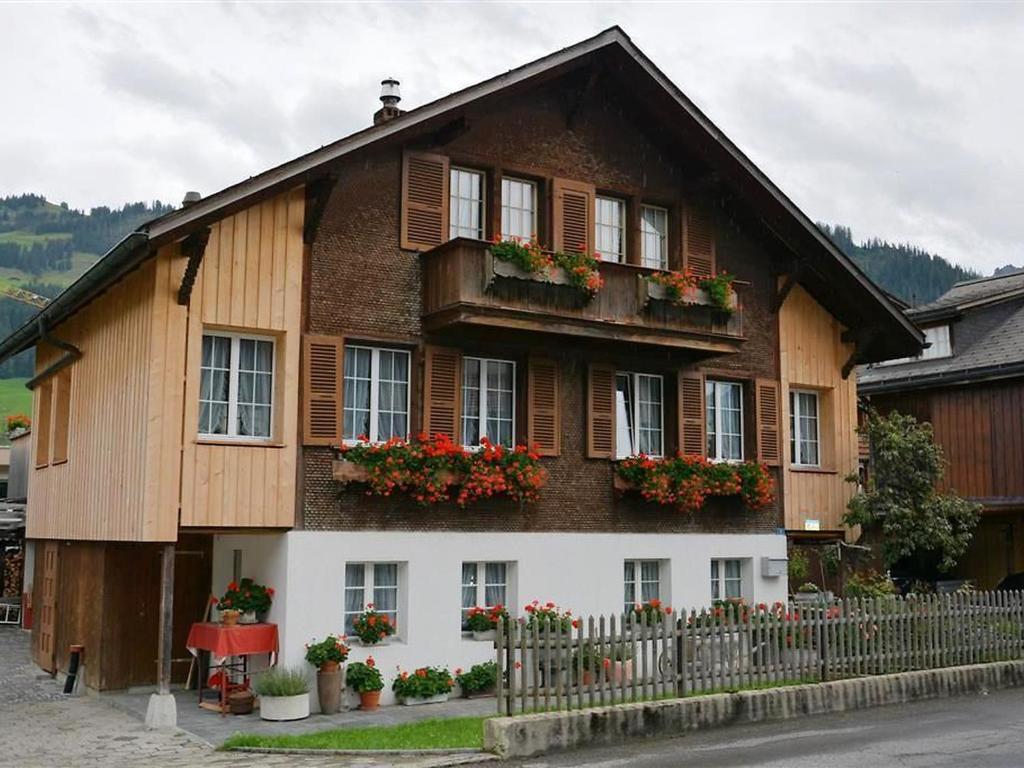 a house with flowers on the windows and a fence at Apartment Beatrice by Interhome in Zweisimmen