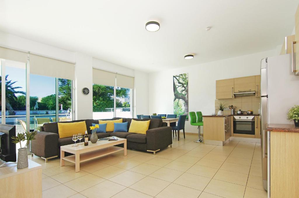 een woonkamer met een bank en een tafel en een keuken bij Calypso - Coralli Beachfront Apartment in Protaras