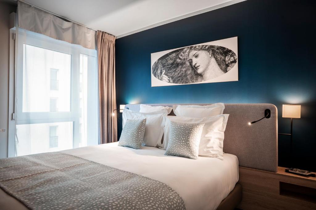 - une chambre avec un grand lit et un mur bleu dans l'établissement Residhome Saint Ouen, à Saint-Ouen