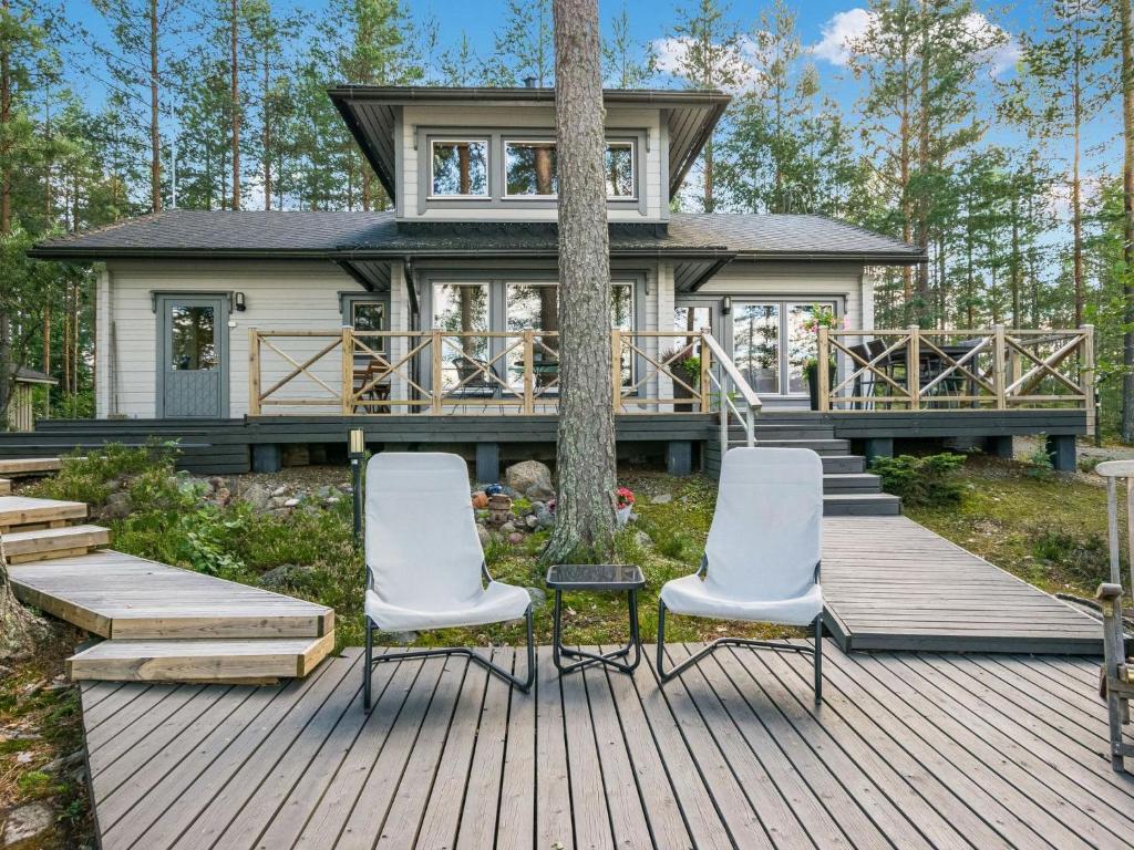 una casa con tre sedie su una terrazza di legno di Holiday Home Kissankulma by Interhome a Mouhu