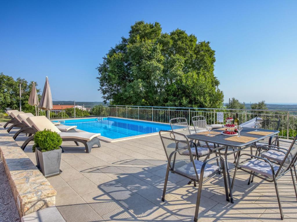 a patio with a table and chairs and a pool at Holiday Home Legović by Interhome in Kaštelir