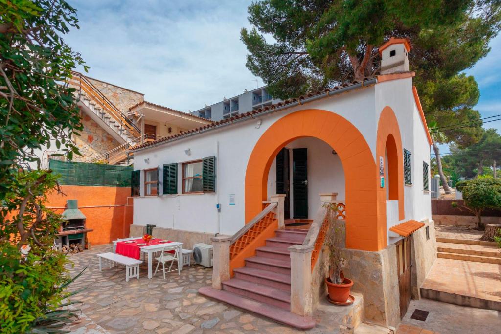 ein kleines weißes Haus mit orangefarbener Tür und Treppe in der Unterkunft Llinya 7 in El Arenal