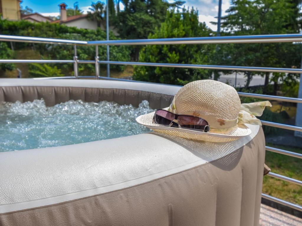 Apartment Aurora by Interhome في بوزت: قبعة ونظارة شمسية جالسة على حافة حوض استحمام ساخن