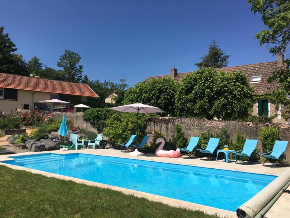 a pool with chairs and umbrellas next to a house at Gites La Tourelle in Uxeau