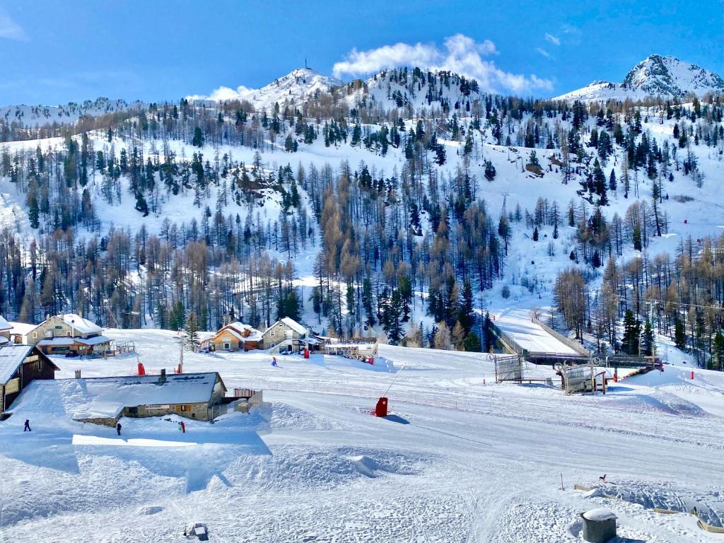 una montaña cubierta de nieve con una pista de esquí con edificios en ISOLA Front de Neige - STUDIO, en Isola 2000