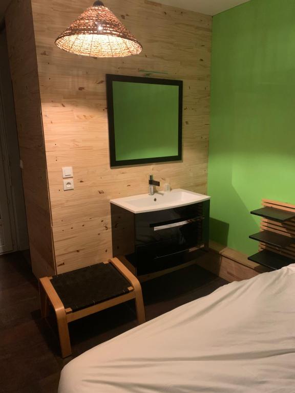 a bedroom with a sink and a green wall at Hotel La Madelon in Le Fenouiller